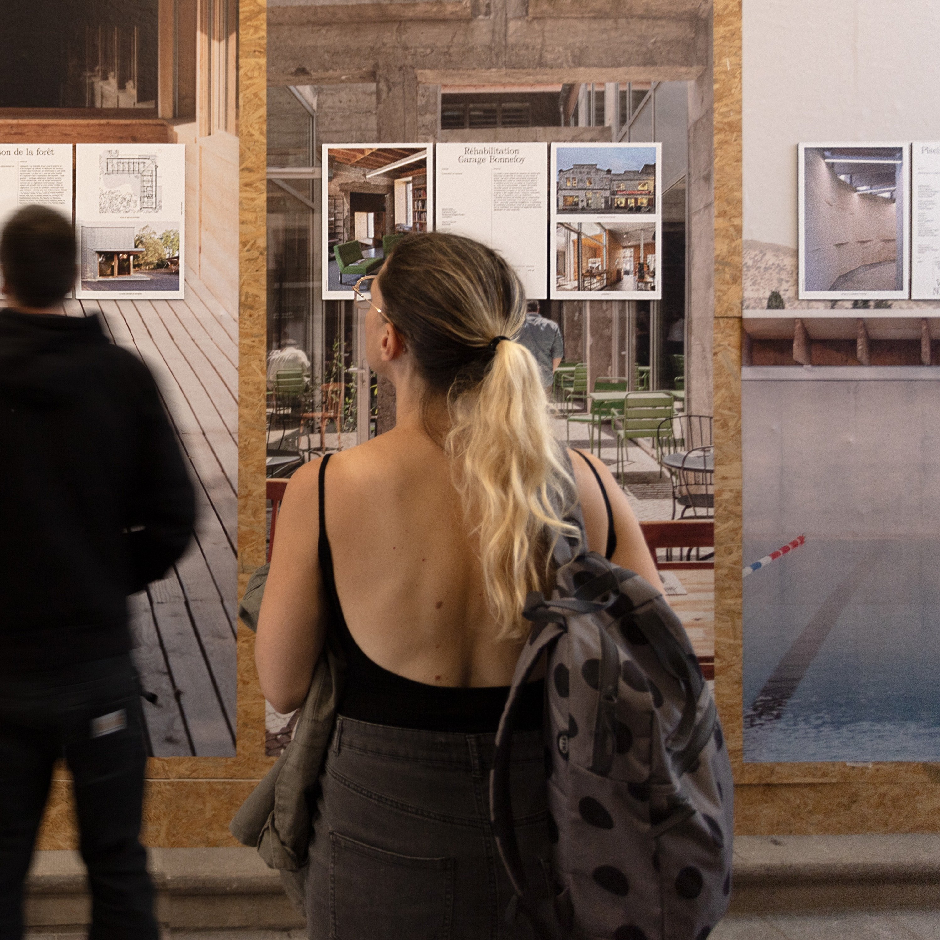 Vue de près des panneaux explicatifs, deux personnes sont en train de lire: de près, ou de loin